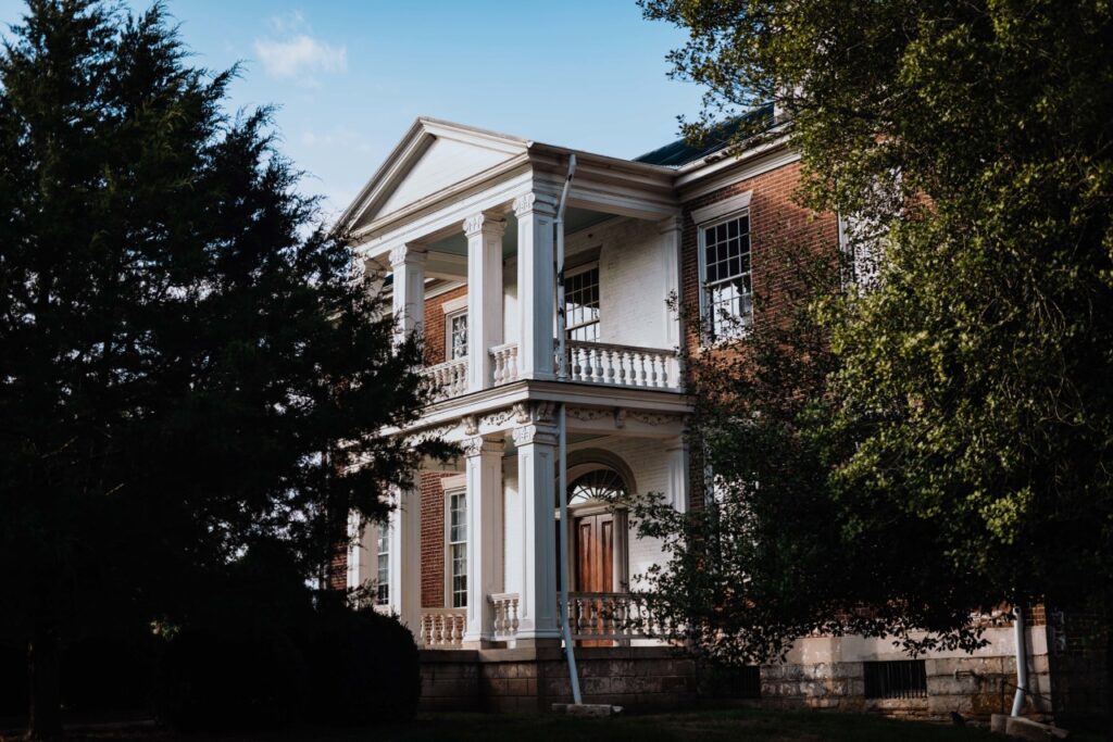 What Every History Lover Must See in Franklin A stately two-story brick house with white columns and a balcony, surrounded by lush greenery in Williamson County, Tennessee.