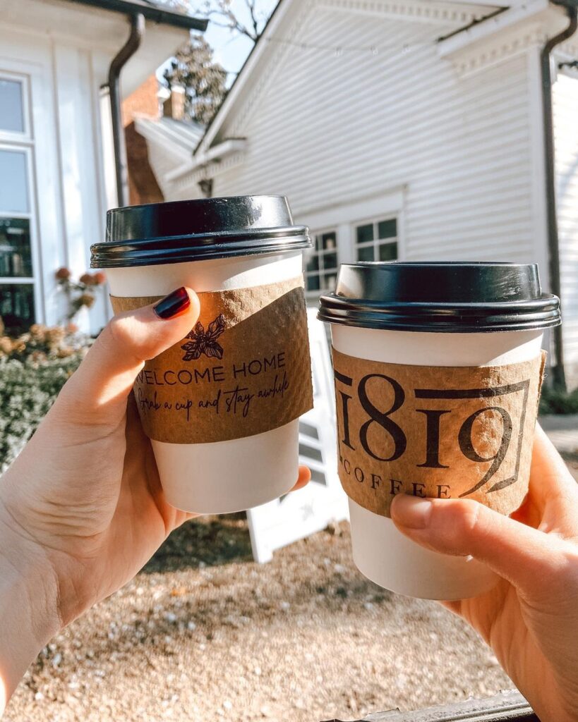 Farm Fresh in Franklin: Where to Find the Best Seasonal & Local Eats This Fall Two hands hold coffee cups with 'Welcome Home' and '1819 Coffee' branding against a white house backdrop in Williamson County, Tennessee.