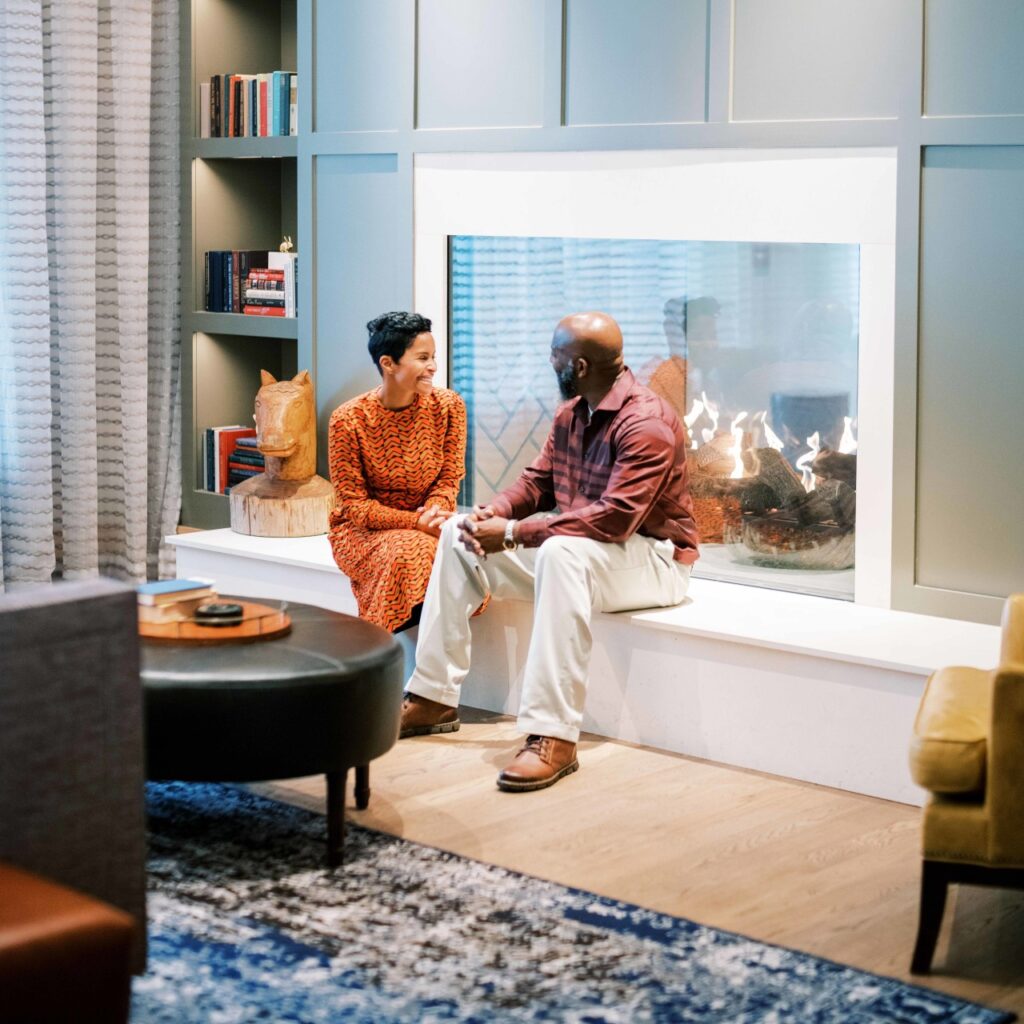 A couple sits by a modern fireplace in a cozy living room with bookshelves in Williamson County, Tennessee.