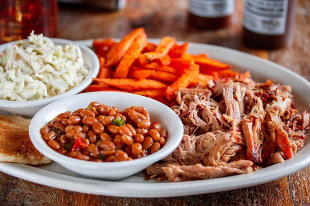 A hearty plate of barbecue featuring pulled pork, baked beans, coleslaw, and sweet potato fries in Williamson County, Tennessee.