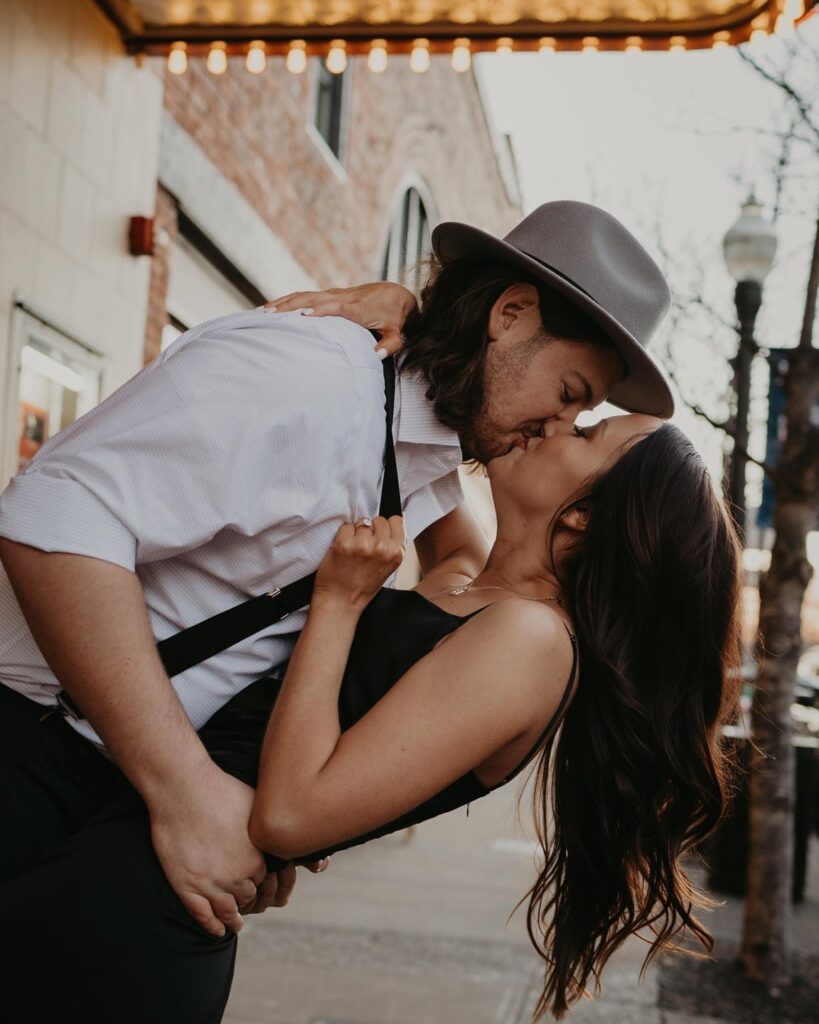 A couple passionately kisses outdoors, with the man wearing a hat and suspenders in Williamson County, Tennessee.
