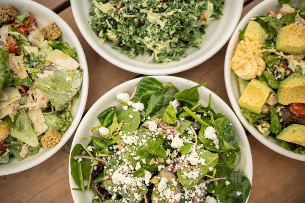 The Heart & Soul of Healthy Food: Chef Bobby Benjamin & Franklin Favorite Herban Market Four bowls of colorful salads with various toppings on a wooden table in Williamson County, Tennessee.