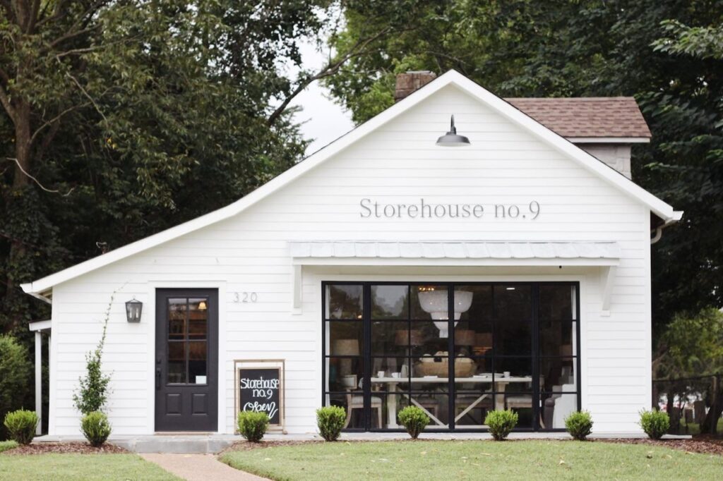 11 Can't-Miss Home Decor Shops with the Best Finds in Franklin A quaint white storehouse with black trim and large windows, surrounded by greenery in Williamson County, Tennessee.