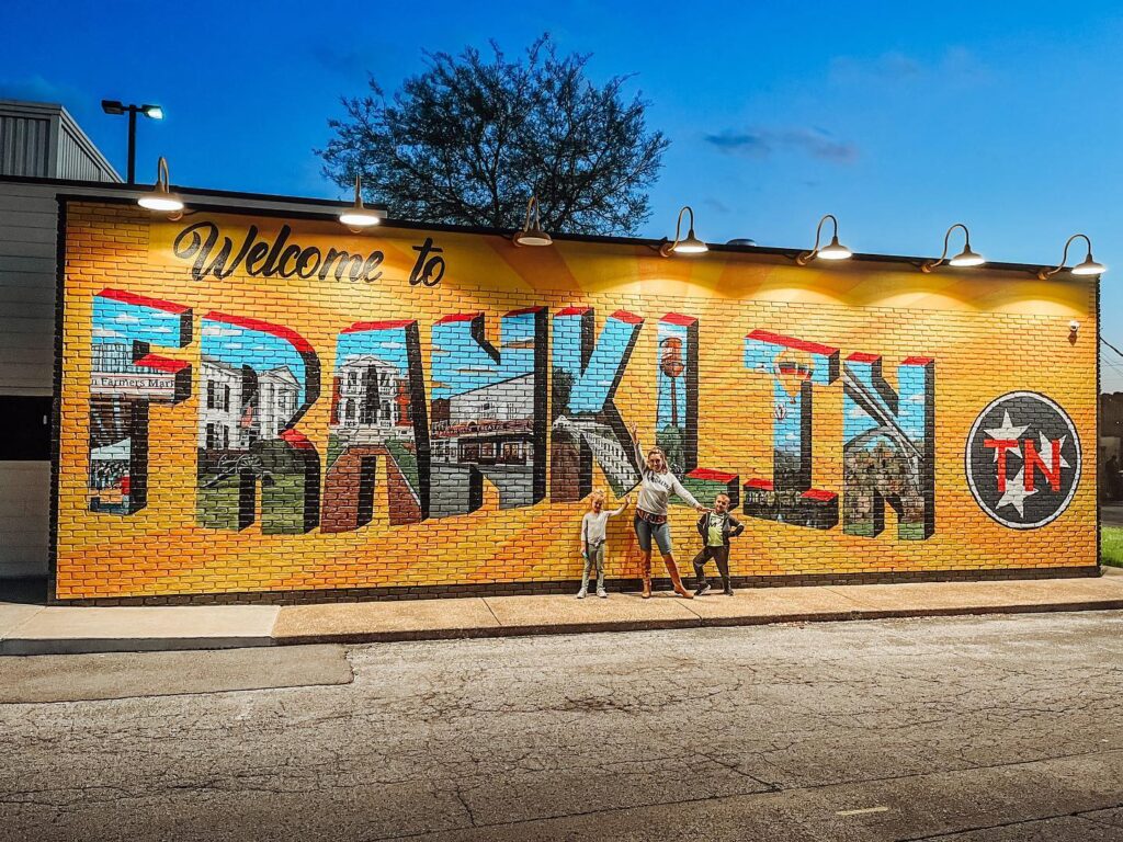 A family stands in front of a colorful mural welcoming visitors to Franklin, TN in Williamson County, Tennessee.