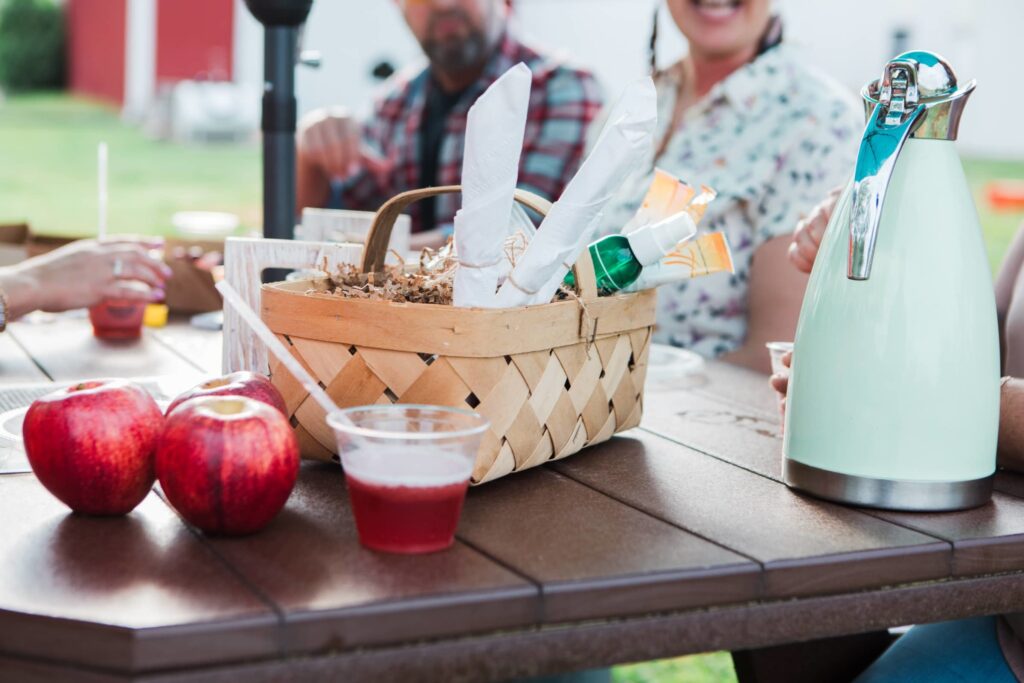 10 Franklin Experiences You'll Want to Add to Your Summer Bucket List A picnic table with a basket of apples, a pitcher of red drink, and a green thermos in Williamson County, Tennessee.