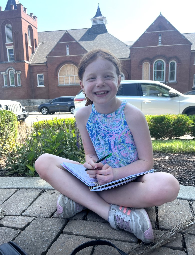 You'll Love This Child's Adorable Review of Franklin's Best Features young girl sitting in front of historic church in quaint downtown area