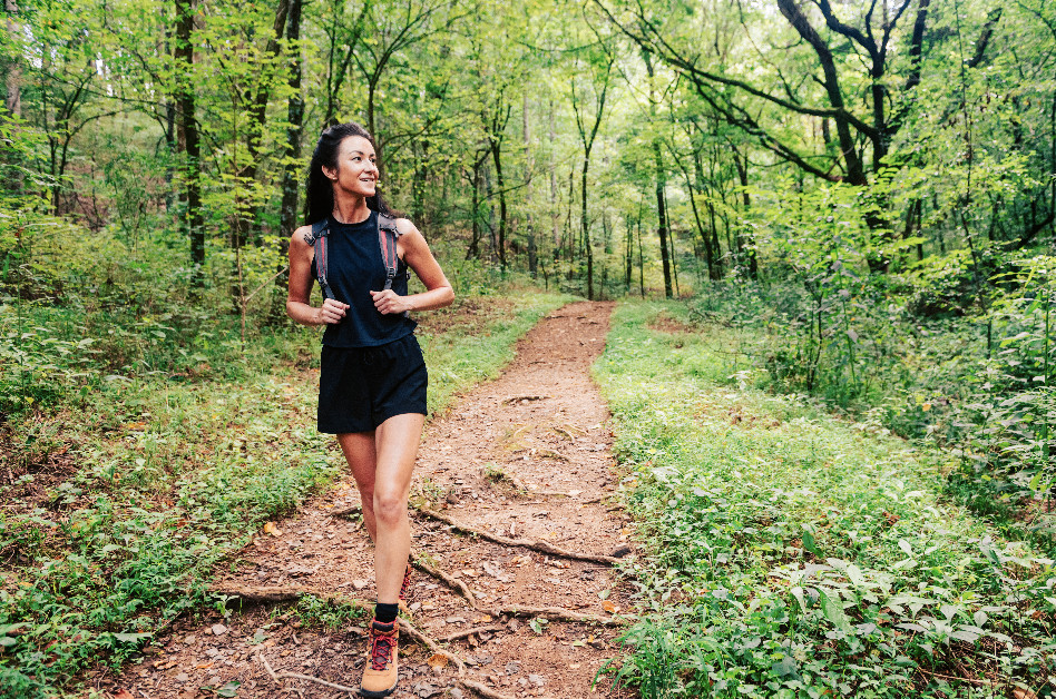 How to Eat Well, Feel Great & Stay Fit on Your Next Franklin Vacation A woman in athletic wear smiles as she hikes a forest trail surrounded by lush greenery in Williamson County, Tennessee.
