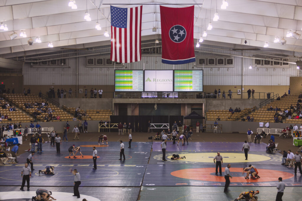 A large indoor wrestling tournament with multiple matches taking place on colorful mats in Williamson County, Tennessee.