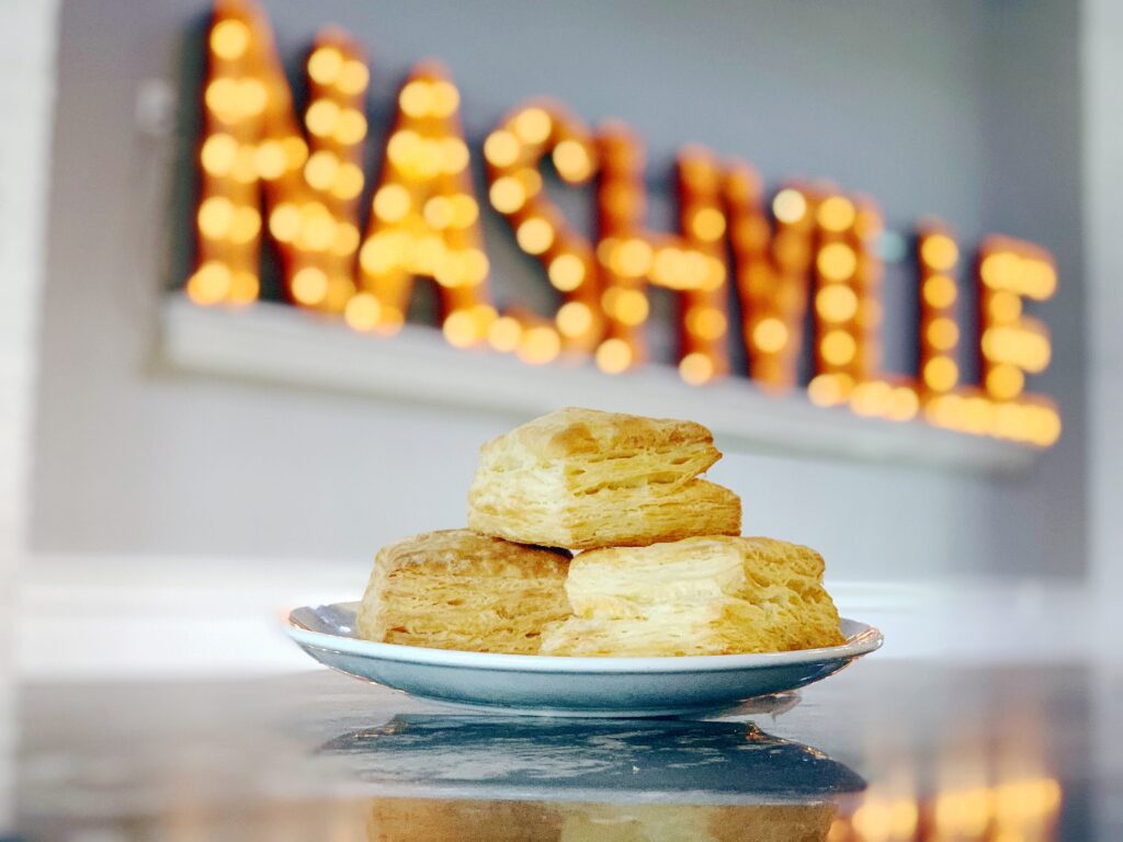 Three golden-brown biscuits stacked on a white plate with a reflective surface in Williamson County, Tennessee.