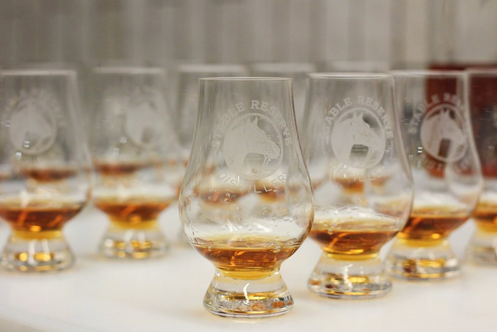 Tasting Experience A row of branded whiskey tasting glasses filled with amber liquid on a white surface in Williamson County, Tennessee.
