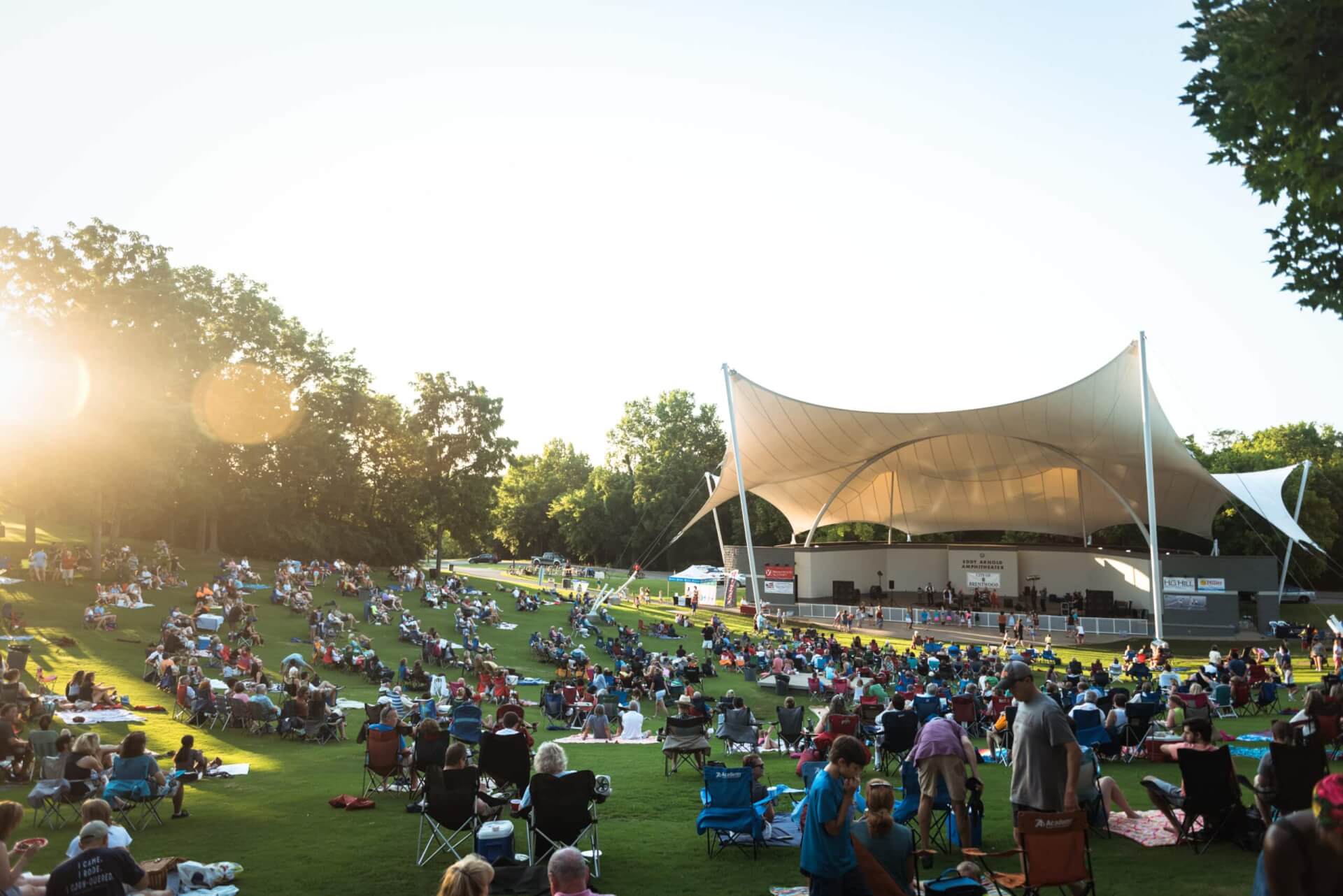 Brentwood A large crowd enjoys an outdoor concert under a white tent at sunset in a grassy park in Williamson County, Tennessee.