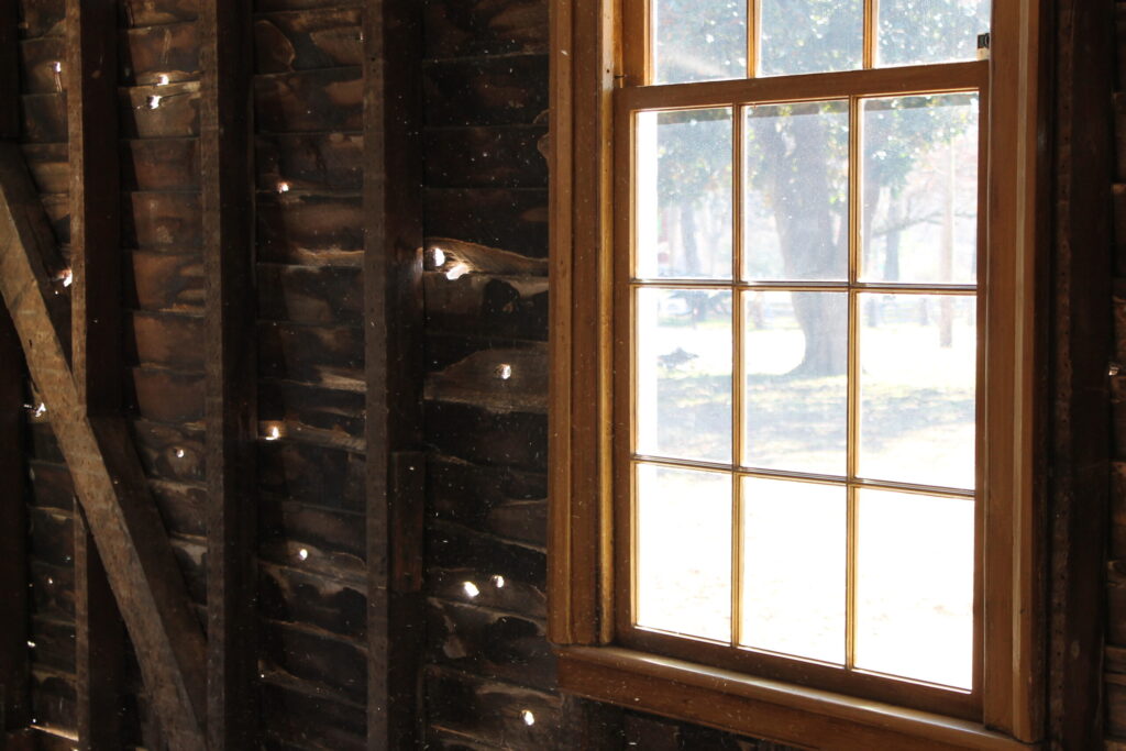 A weathered wooden building with a window showing signs of decay and bullet holes in Williamson County, Tennessee.
