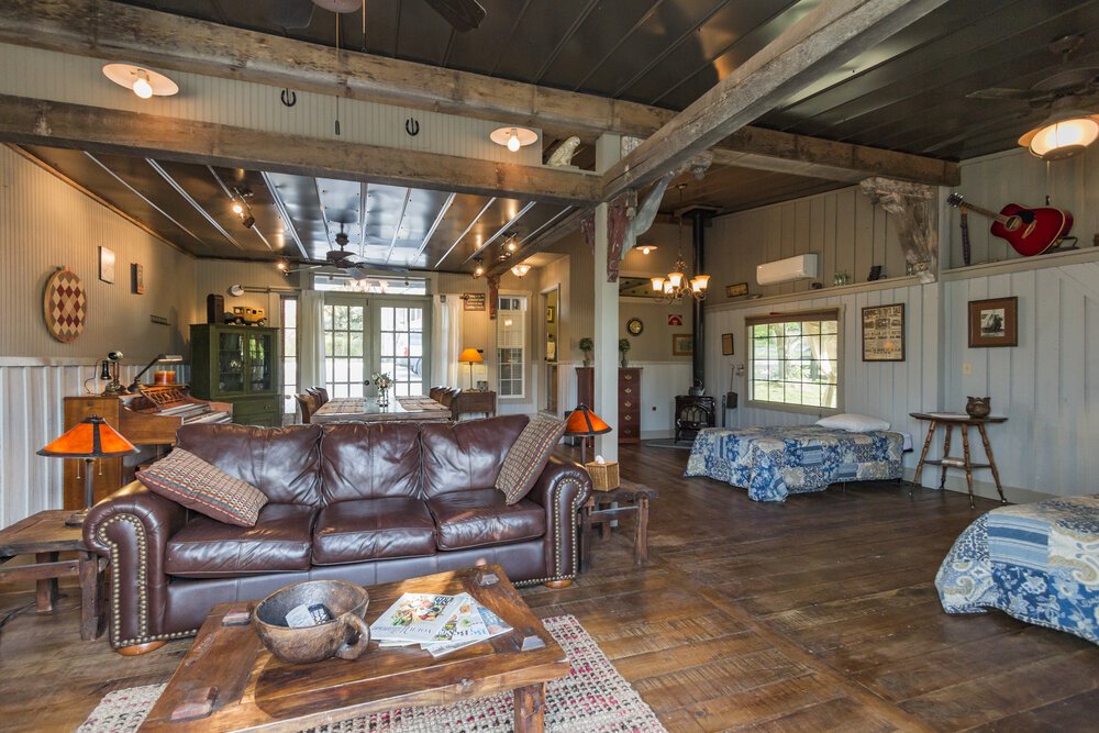 A rustic living room with exposed beams, leather sofa, and wooden floors in Williamson County, Tennessee.