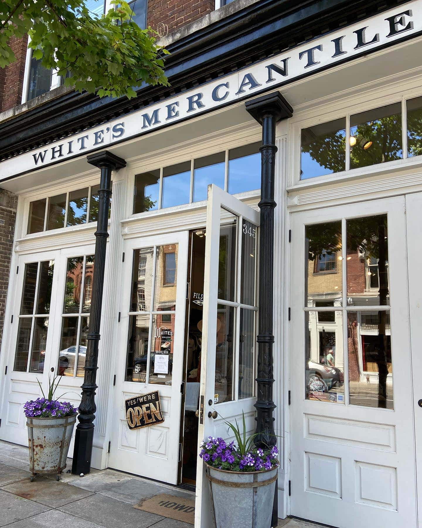 White's Mercantile storefront with open doors, potted plants, and a sign indicating it's open in Williamson County, Tennessee.