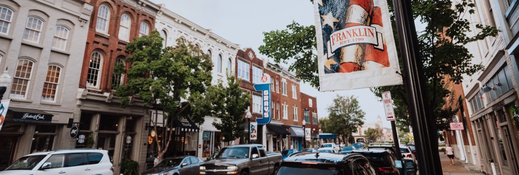 Communities A bustling downtown street lined with colorful buildings and parked cars in Williamson County, Tennessee.