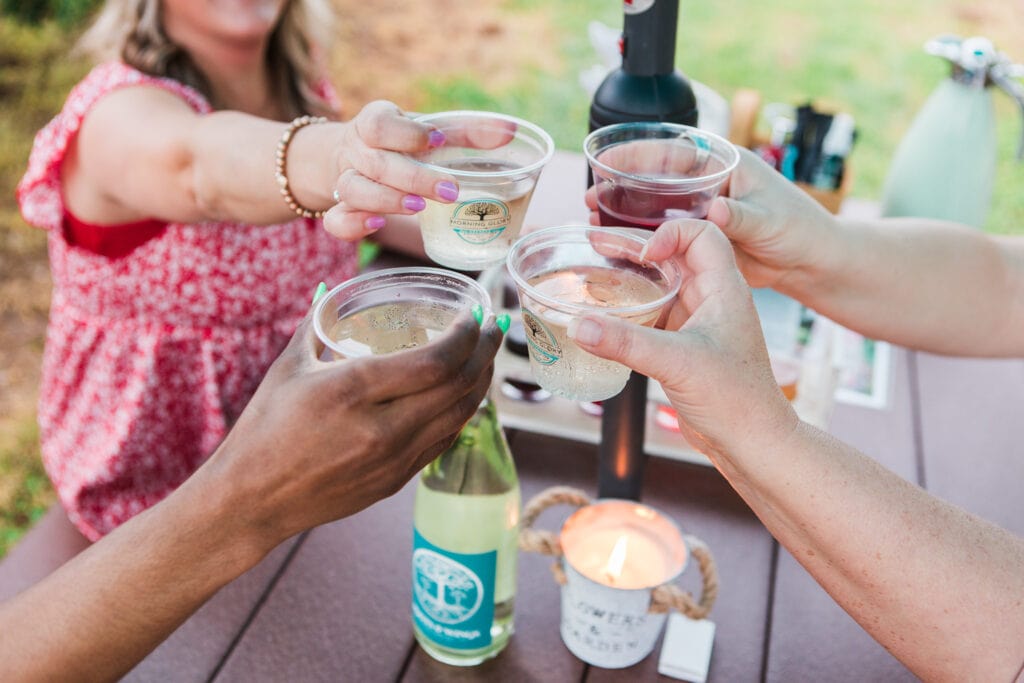 The Top 9 Franklin Events That Will Make Your Summer Spectacular Four women cheerfully clink plastic cups filled with beverages at an outdoor table in Williamson County, Tennessee.