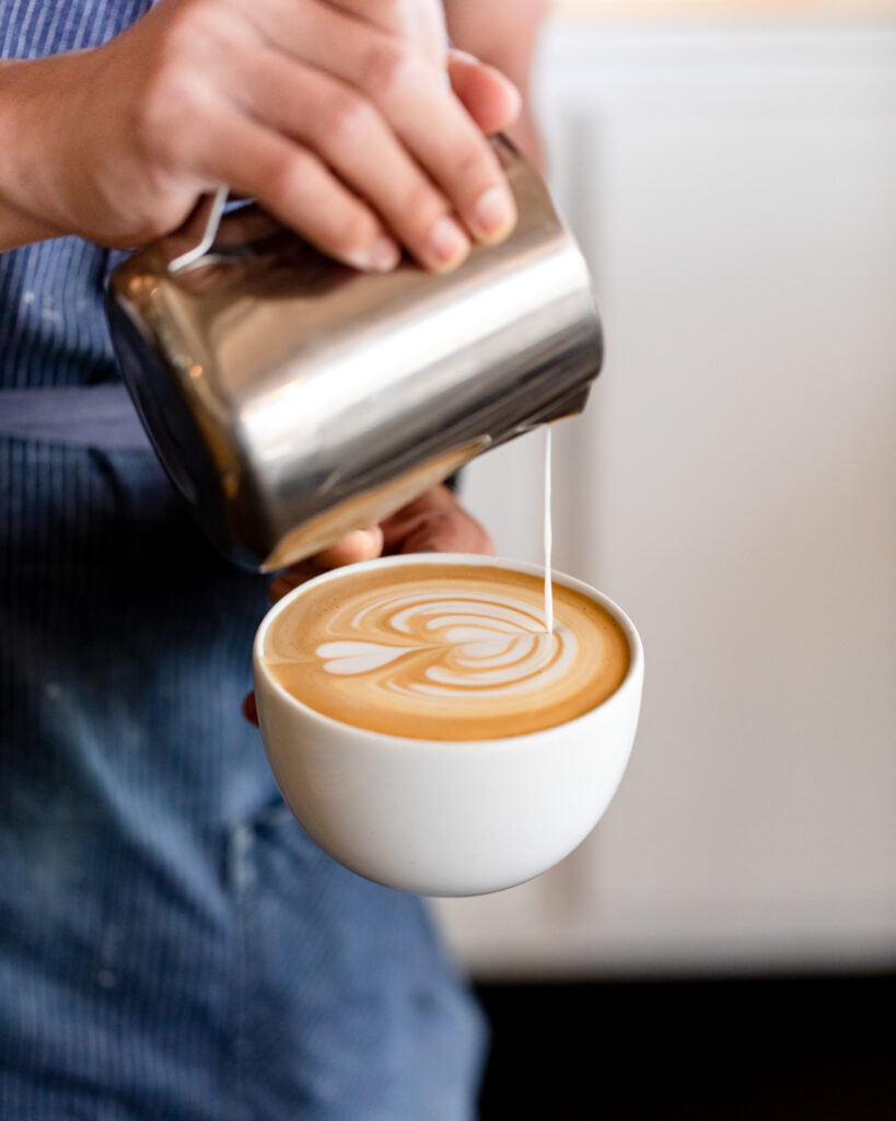 Barista pours steamed milk into espresso, creating latte art in a white cup in Williamson County, Tennessee.
