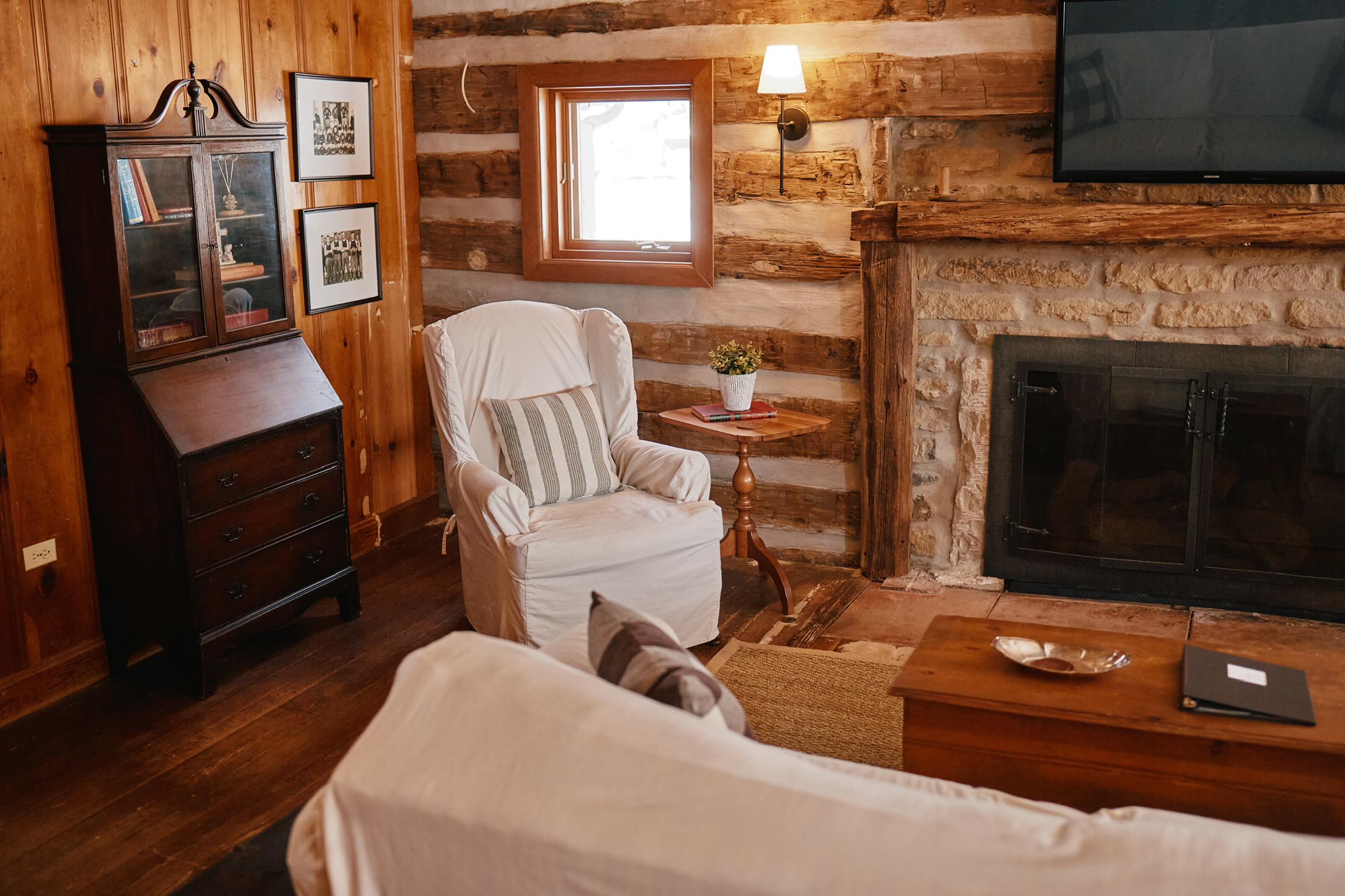 Rustic living room with log walls, stone fireplace, white furniture, and wooden accents in Williamson County, Tennessee.