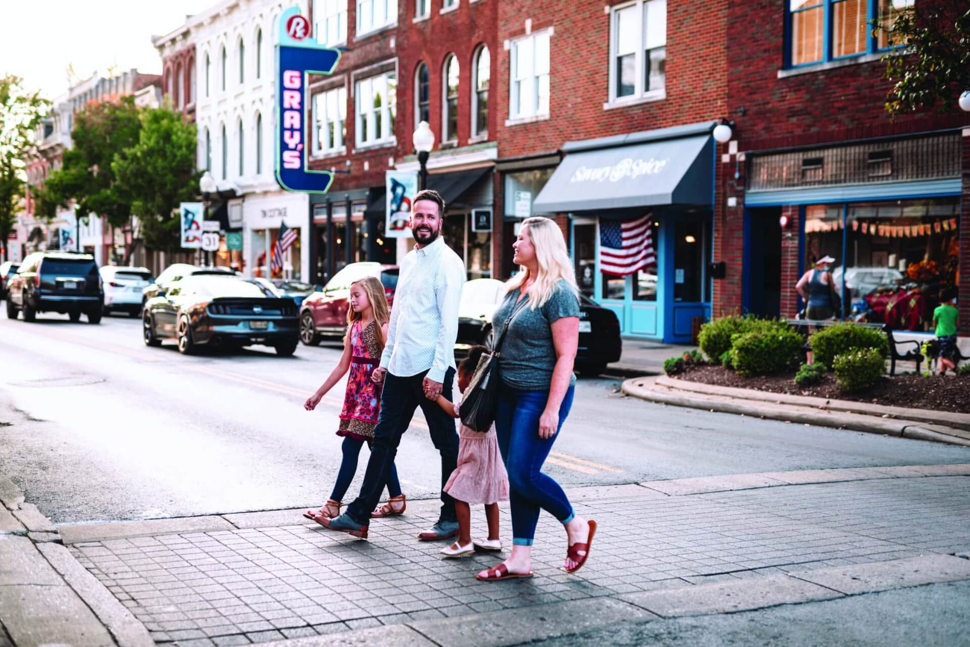 A family of four, including two children, walks across a busy street in a small town in Williamson County, Tennessee.