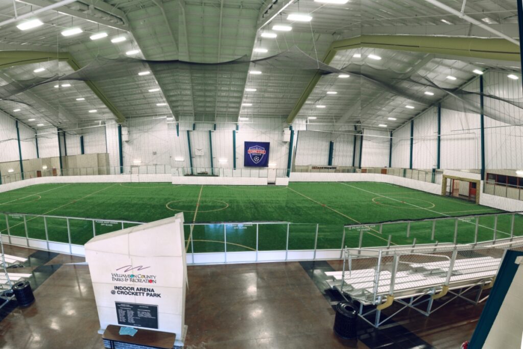 An indoor sports arena with a large artificial turf field and spectator seating in Williamson County, Tennessee.