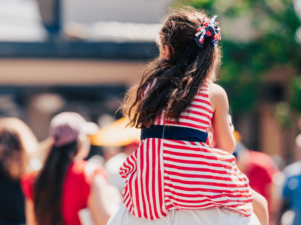 Your Best Summer Break Ever: Top Kid-Friendly Activities in Franklin, Tennessee A young girl in a red, white, and blue striped dress sits on someone's shoulders at a crowded outdoor event in Williamson County, Tennessee.