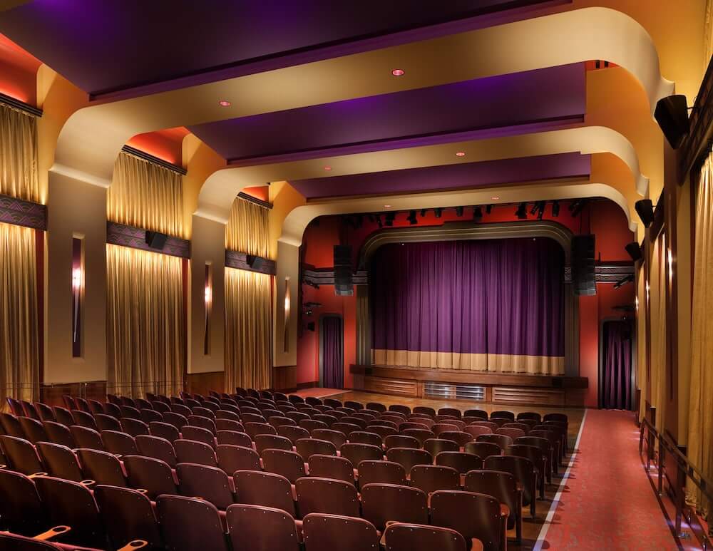 An ornate theater with red and purple seating, a stage, and golden curtains in Williamson County, Tennessee.
