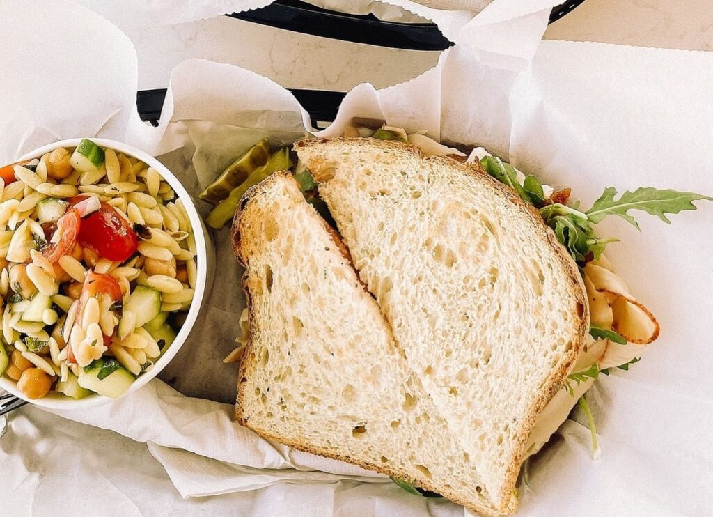 A sandwich with turkey, lettuce, and tomato on whole grain bread, accompanied by a side salad in Williamson County, Tennessee.
