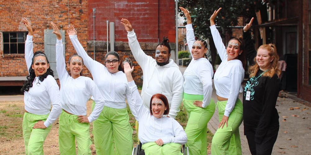 Events A diverse group of dancers in white tops and bright green pants perform an energetic routine outdoors, with one member in a wheelchair in Williamson County, Tennessee.