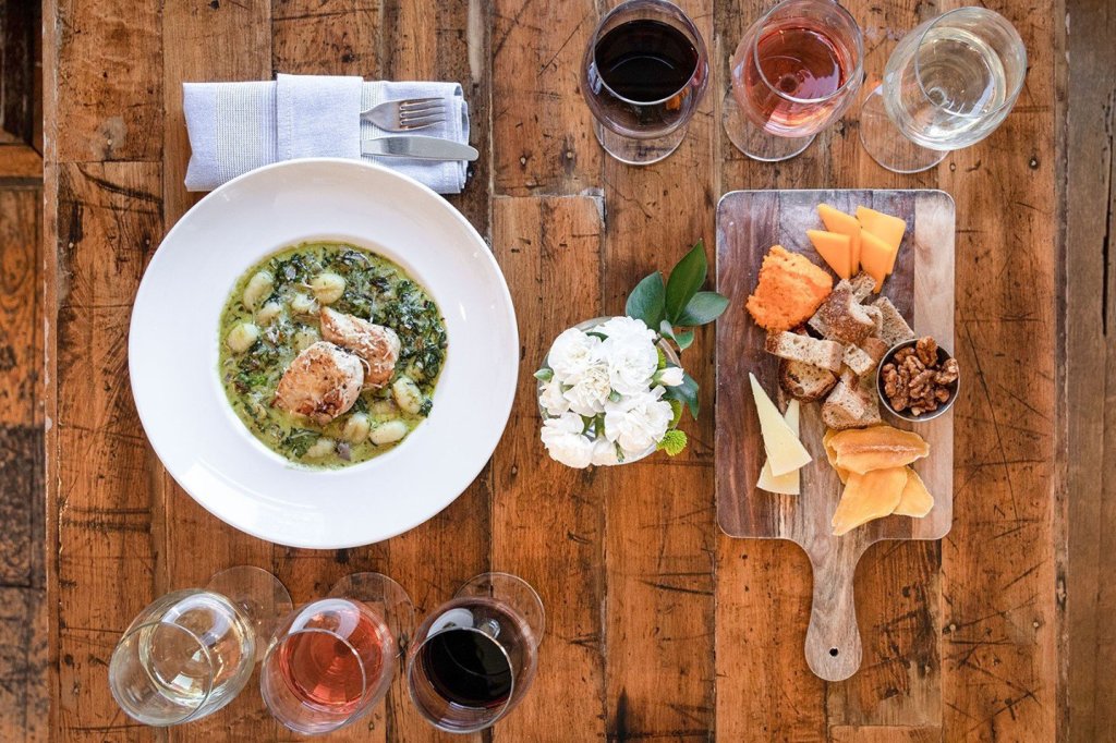 A rustic wooden table set with a gourmet meal, wine glasses, and a cheese board in Williamson County, Tennessee.