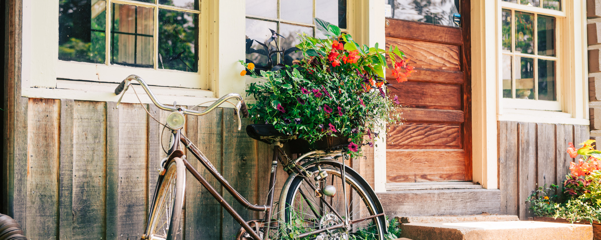 A vintage bicycle with a flower basket rests against a wooden house with a red door in Williamson County, Tennessee.