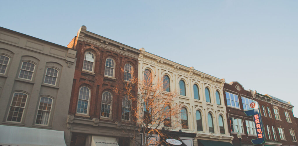 A row of historic buildings with ornate facades and large windows, bathed in warm sunlight in Williamson County, Tennessee.