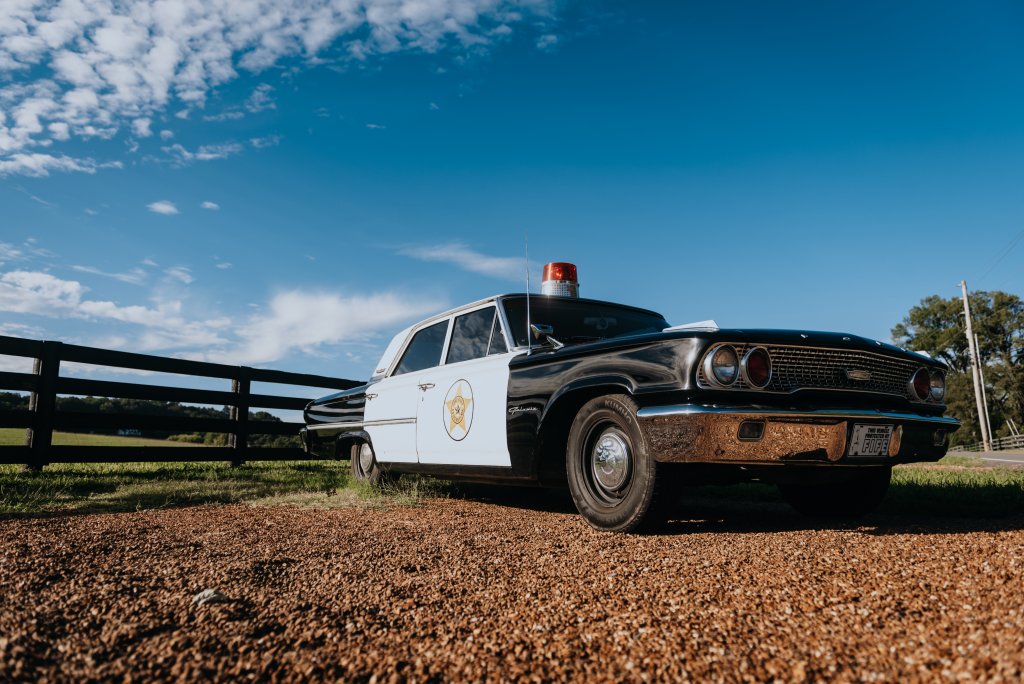 12 Amazing Things to Do in Charming Leiper's Fork, Tennessee A vintage black and white police cruiser parked on gravel near a wooden fence in Williamson County, Tennessee.