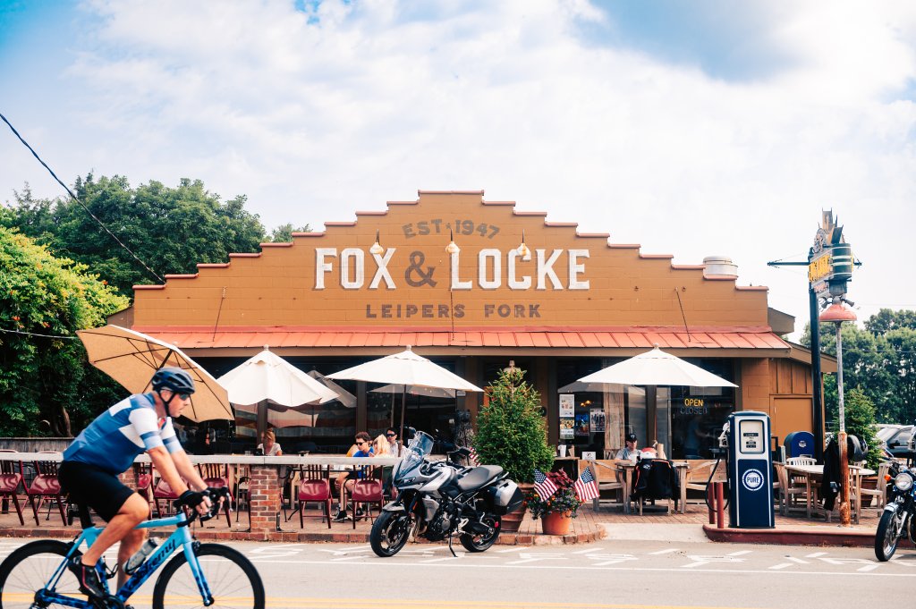 12 Amazing Things to Do in Charming Leiper's Fork, Tennessee A cyclist rides past a restaurant with outdoor seating and a vintage gas pump in Williamson County, Tennessee.