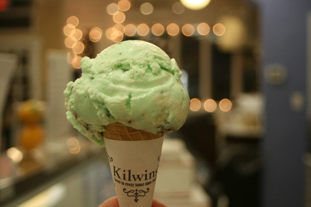 A hand holds a green ice cream cone with a generous scoop of mint chocolate chip ice cream in Williamson County, Tennessee.