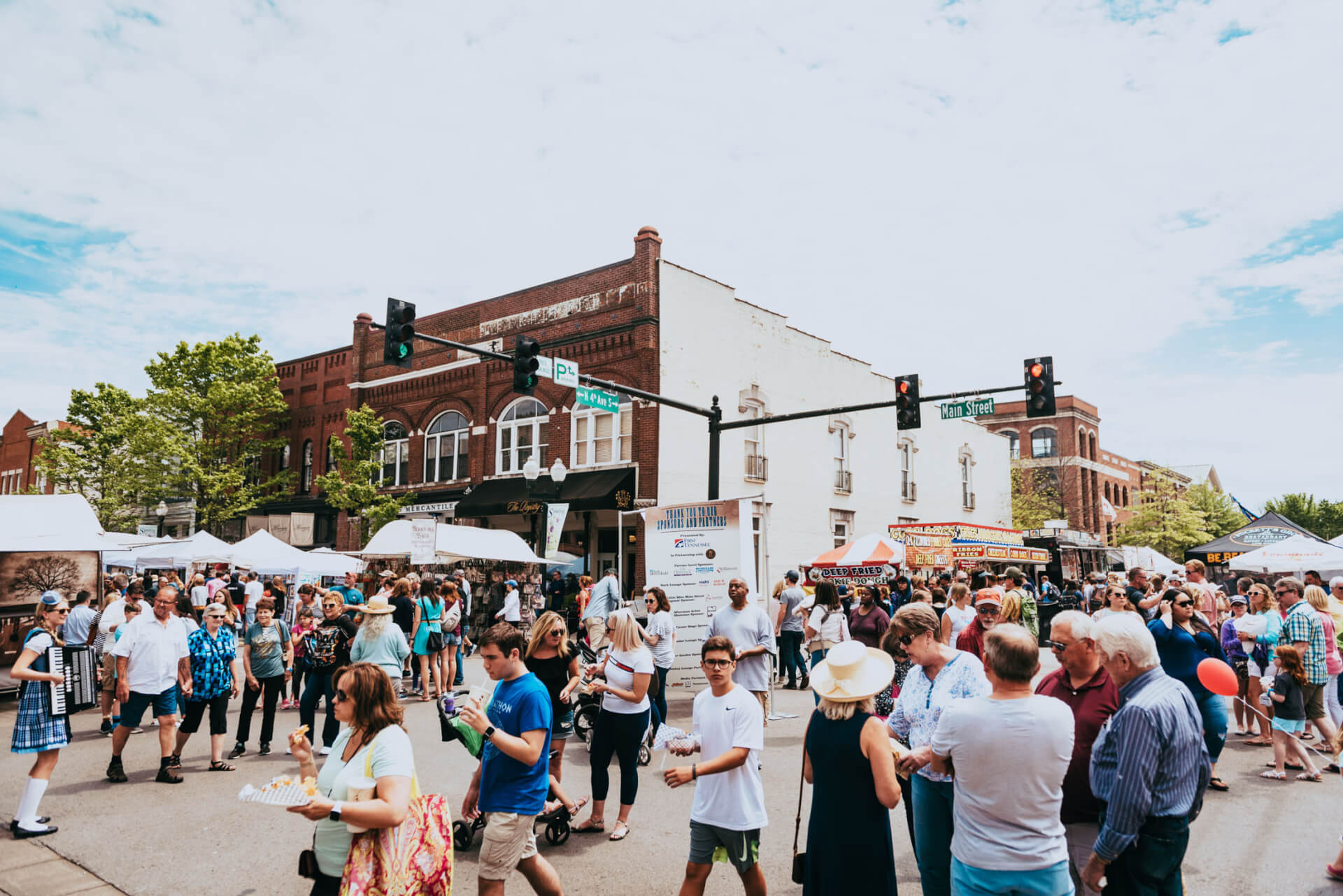 Main Street Festival A bustling outdoor market fills a town square with people browsing stalls, enjoying food, and listening to live music under a clear blue sky in Williamson County, Tennessee.