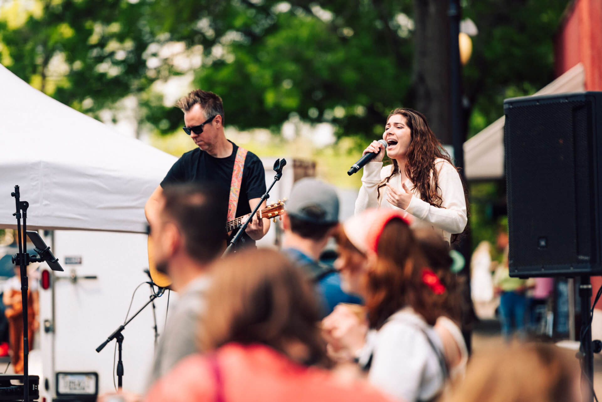 Main Street Festival A lively outdoor concert with a band performing under a white tent, surrounded by an enthusiastic crowd enjoying the music in Williamson County, Tennessee.