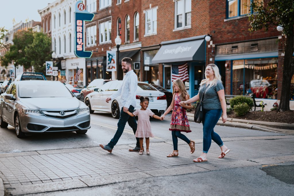A family of four, including a young girl, crosses a busy street in a small town in Williamson County, Tennessee.