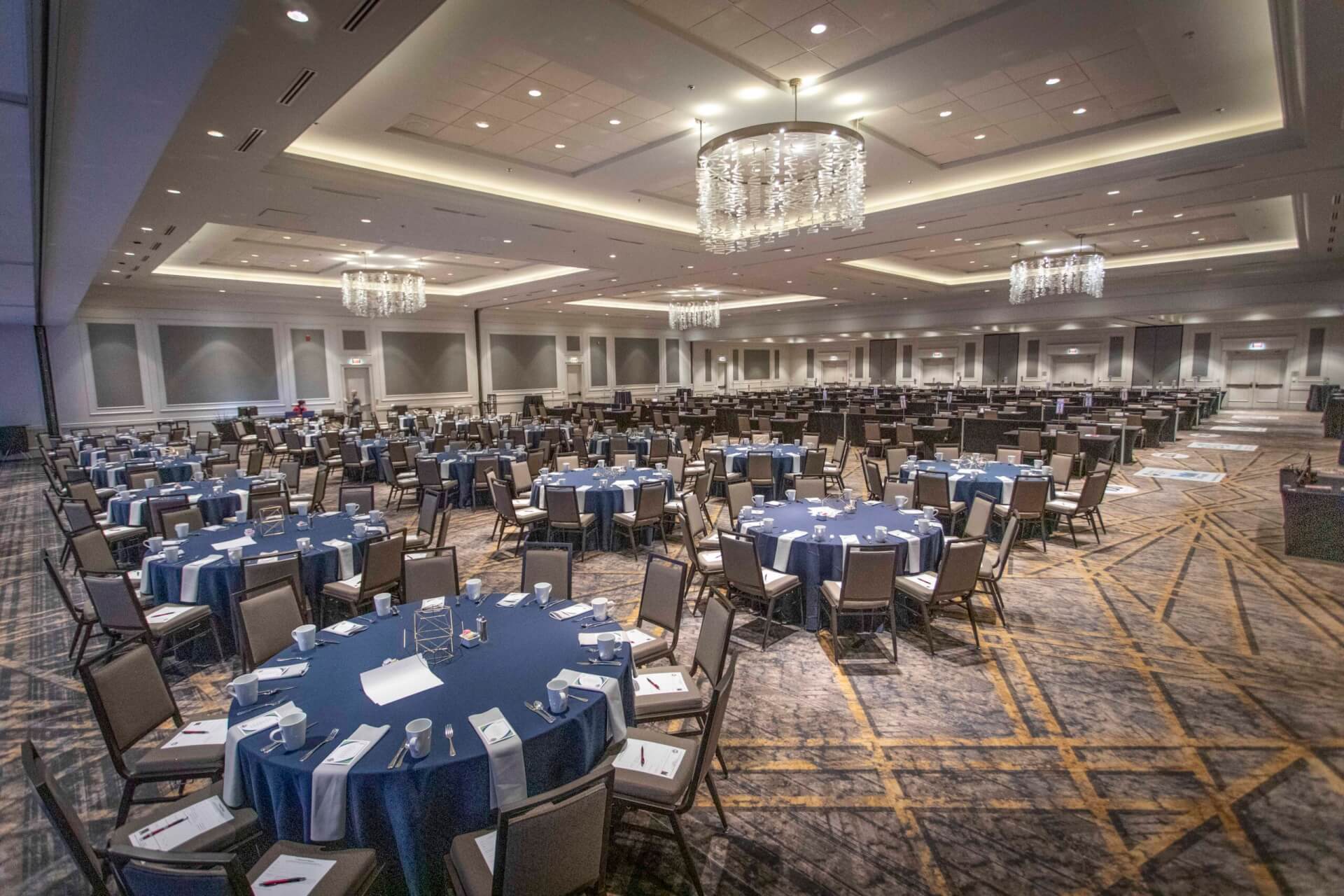 A spacious banquet hall with round tables, blue tablecloths, and chandeliers in Williamson County, Tennessee.