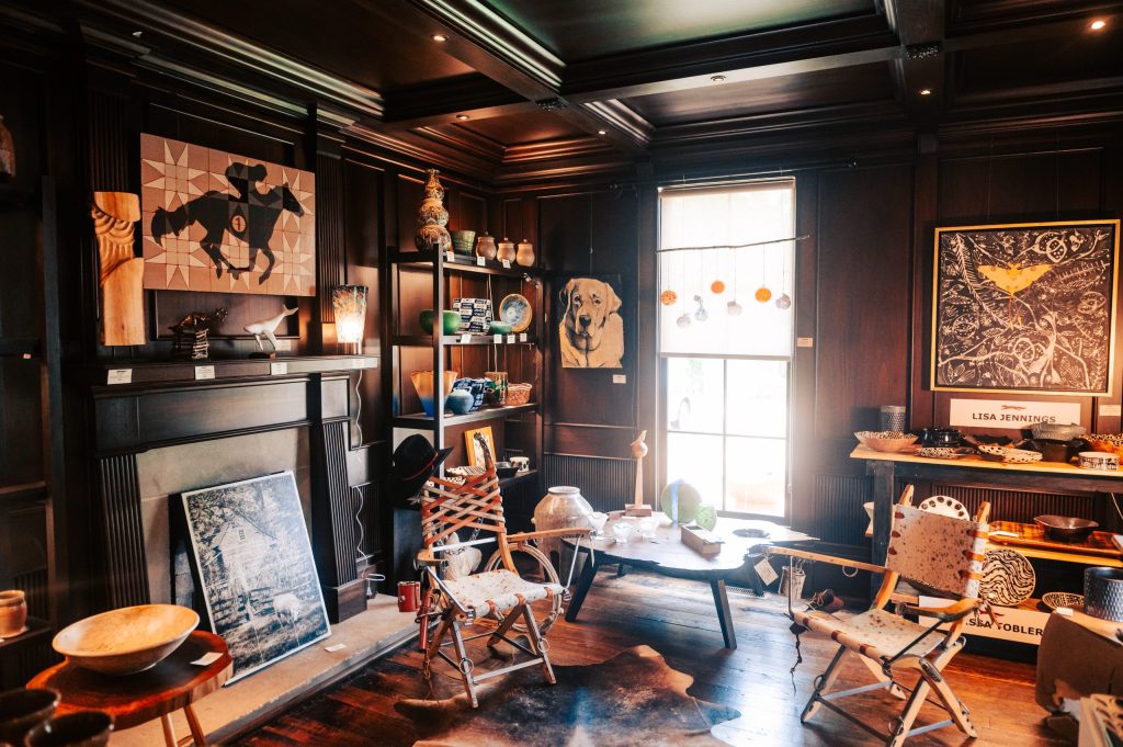 A rustic room with wooden walls, a fireplace, and eclectic furniture and art in Williamson County, Tennessee.