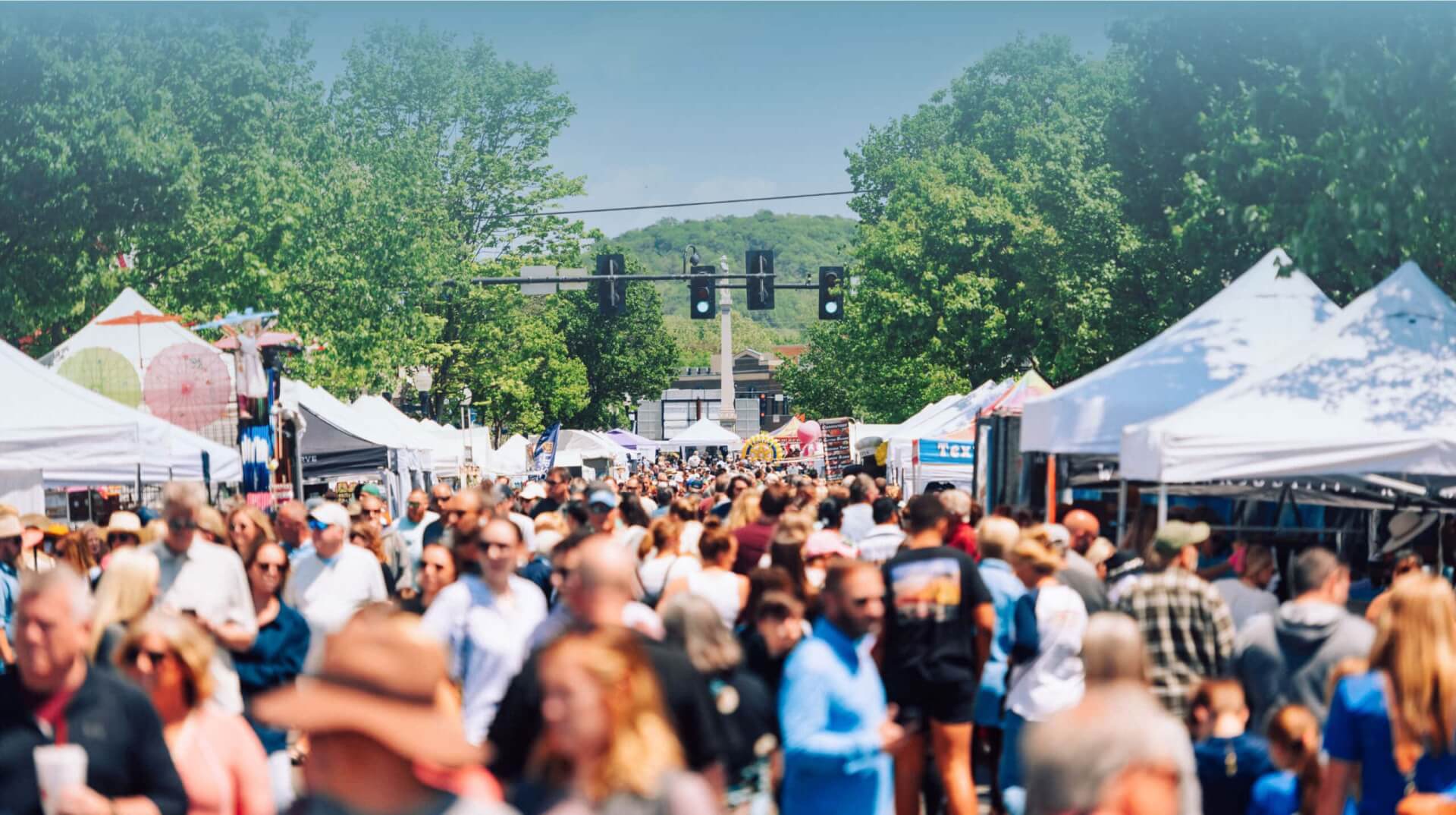 A bustling outdoor market with white tents, filled with people shopping and browsing in Williamson County, Tennessee.