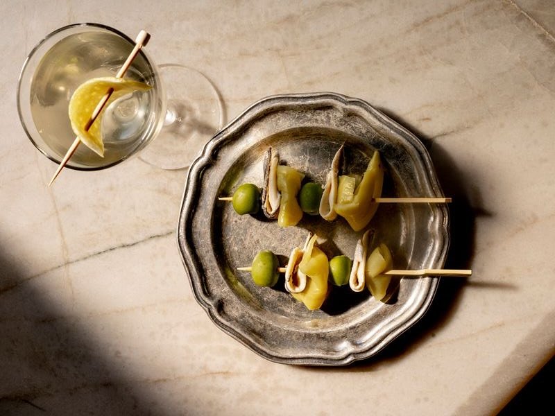 5 Healthy Franklin Restaurants You Must Try A martini glass with a lemon twist and a plate of stuffed olives and pickles on a marble surface in Williamson County, Tennessee.