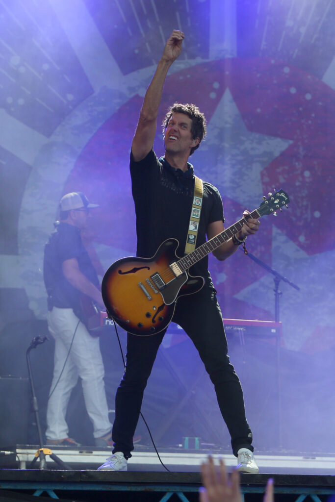 A musician passionately plays an electric guitar on stage, arm raised in triumph in Williamson County, Tennessee.