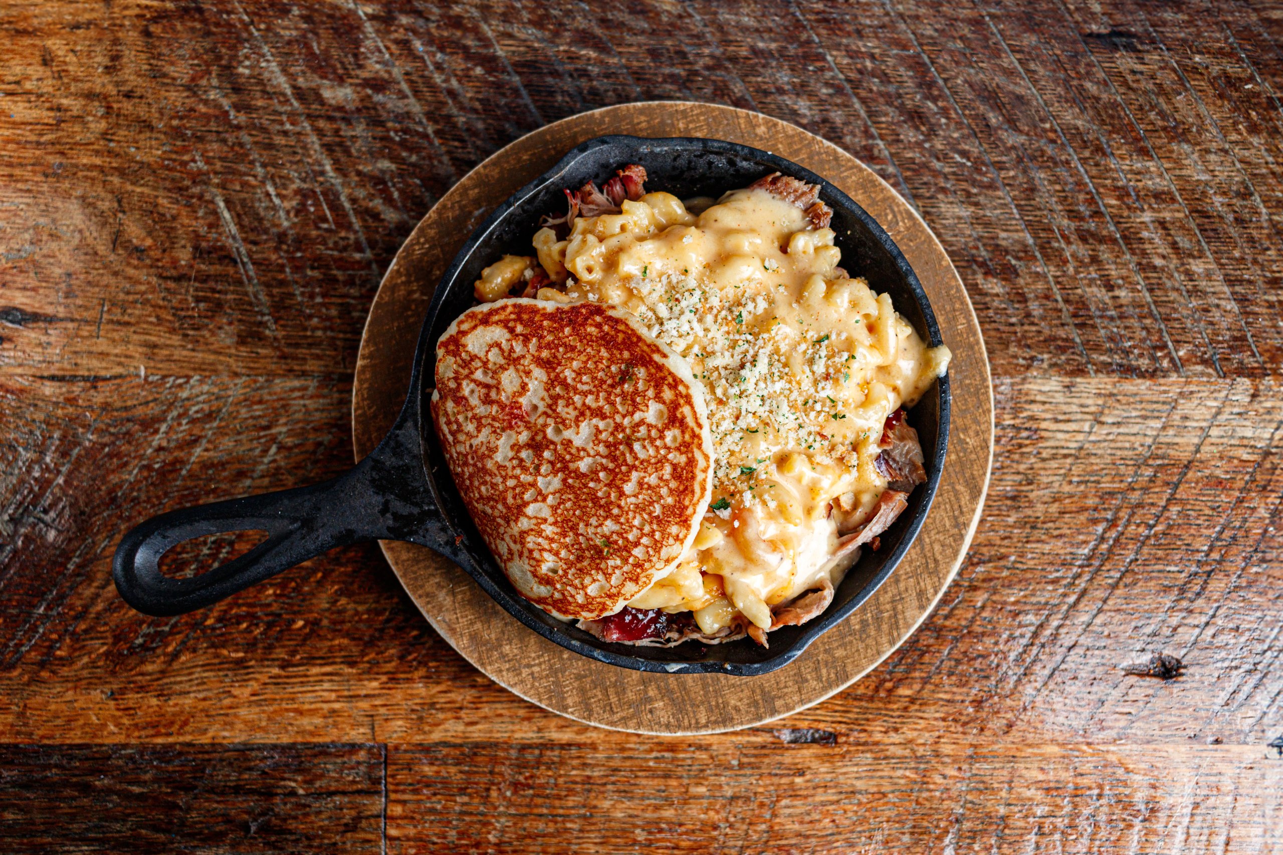 A skillet filled with macaroni and cheese topped with a golden pancake and sprinkled with herbs in Williamson County, Tennessee.