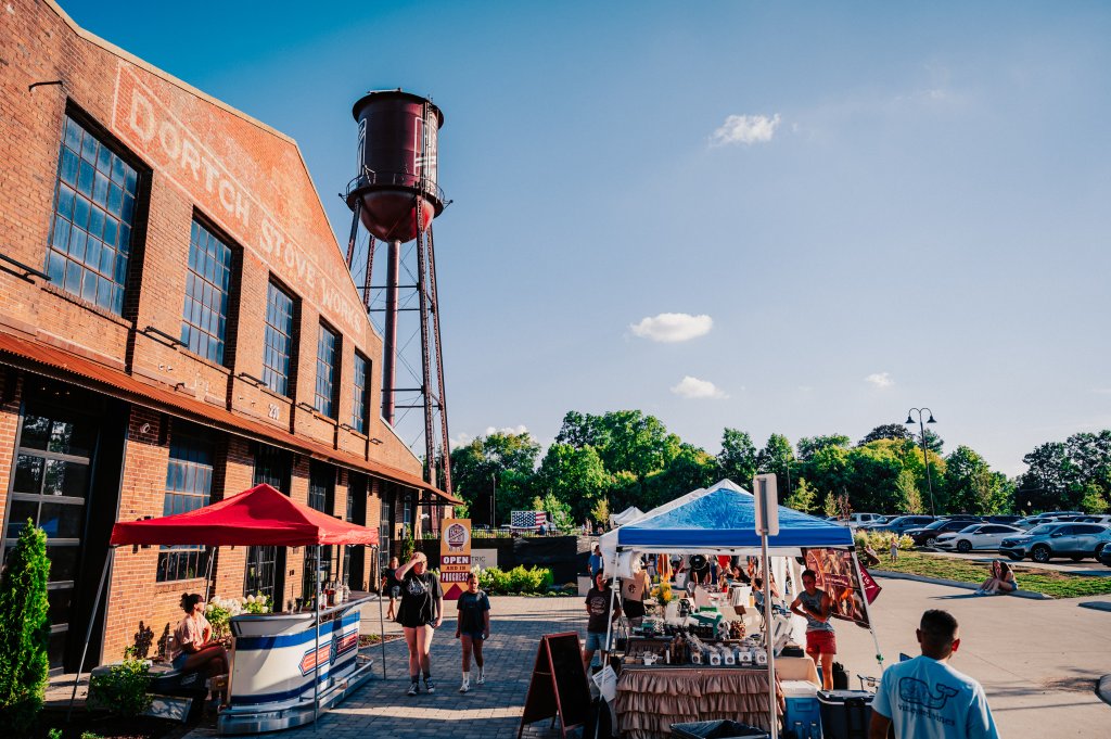 Discover 12 Fun Things To Do With Young Kids in Franklin, TN A bustling outdoor market with colorful tents and vendors set up in front of a historic brick building and a vintage water tower in Williamson County, Tennessee.