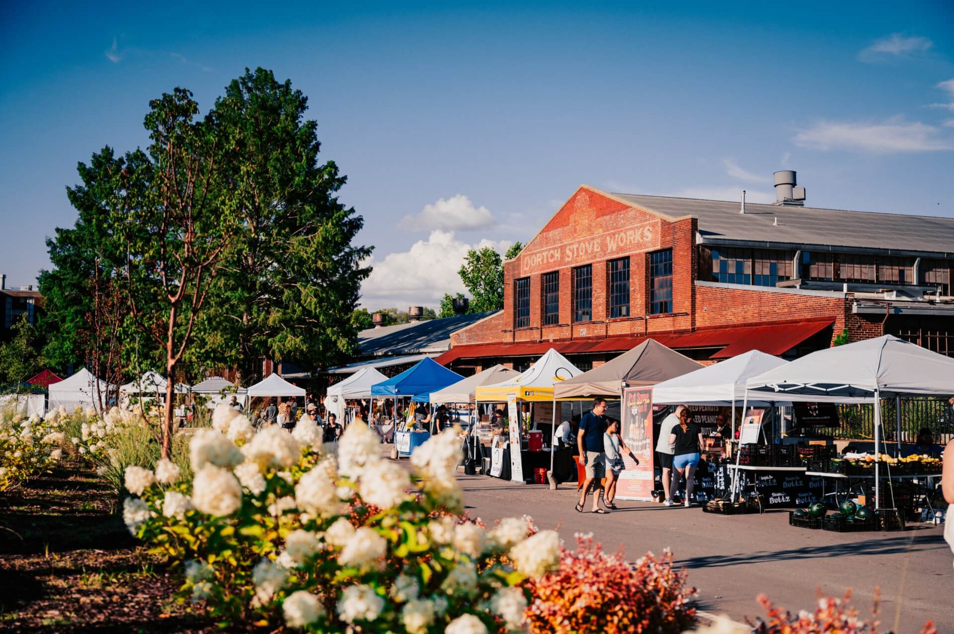 Outdoor market with colorful tents, people shopping, and a historic brick building in the background in Williamson County, Tennessee.