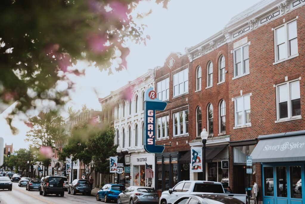 A bustling downtown street with vintage signs, brick buildings, and parked cars in Williamson County, Tennessee.