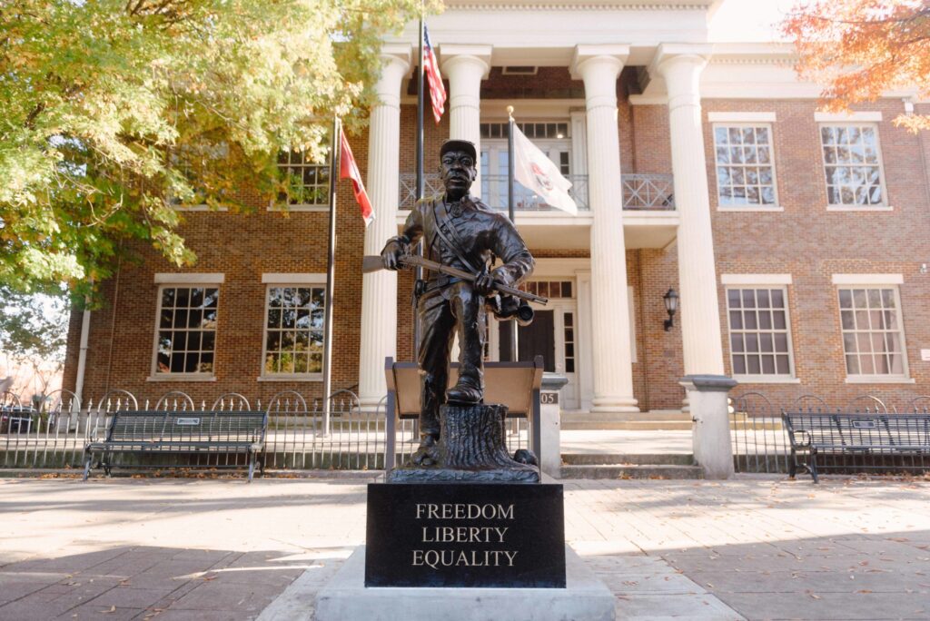 The Story of Franklin, Tennessee's March to Freedom Statue A statue of a soldier stands in front of a brick building with columns and flags in Williamson County, Tennessee.