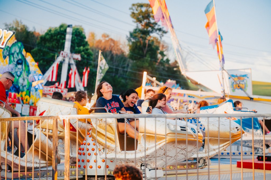 A group of friends enjoys a thrilling ride on a spinning amusement park attraction, surrounded by vibrant lights and festive decorations in Williamson County, Tennessee.