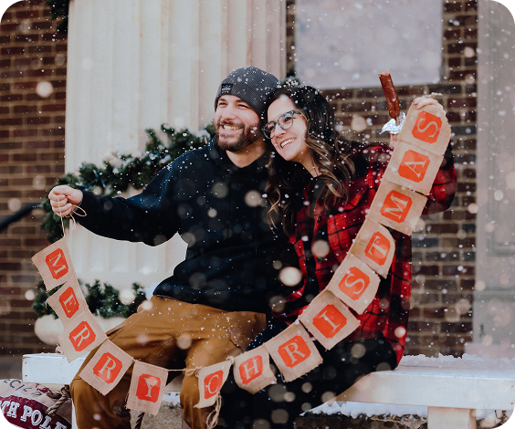 Dickens of a Christmas A couple sits on a snowy bench, holding a 'Merry Christmas' banner in Williamson County, Tennessee.