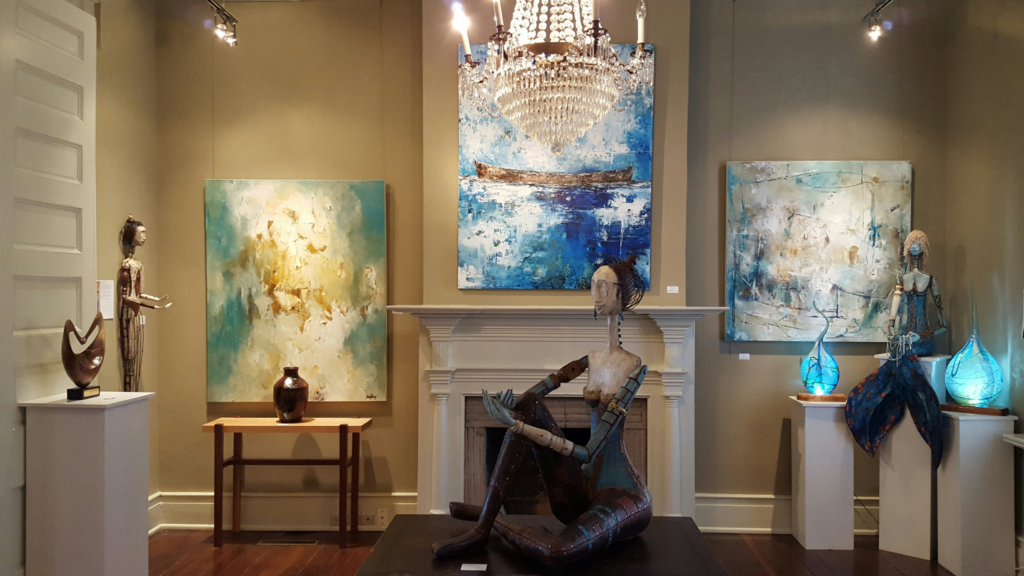 Art gallery with abstract paintings, sculptures, and a chandelier over a fireplace in Williamson County, Tennessee.